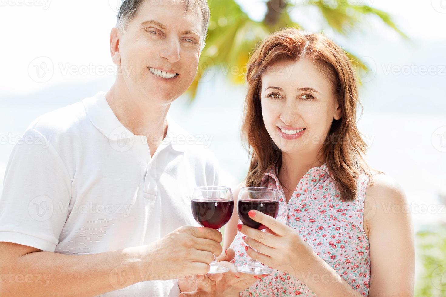 Happy people concept in summer vacation  beautiful middle-aged couple drink wine on the sea background photo