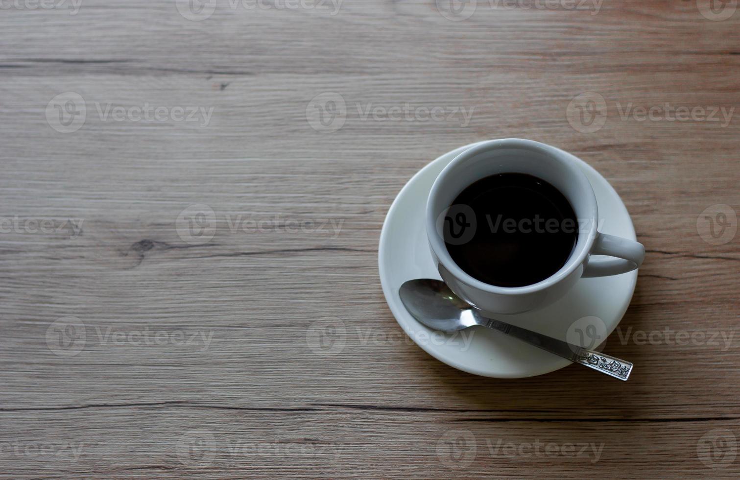 café en una taza blanca sobre una mesa de madera en un café con fondo de iluminación foto