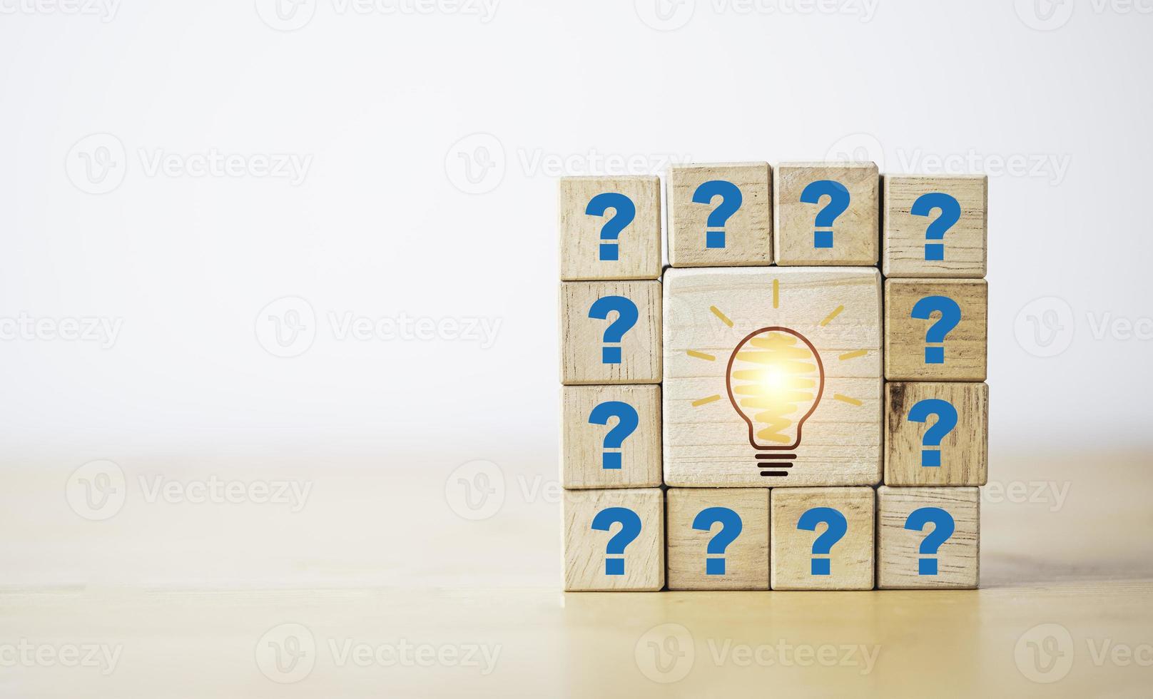 dibujar una pantalla de impresión de bombilla en un bloque de cubo de madera entre el signo de interrogación para el concepto de pregunta y respuesta. foto