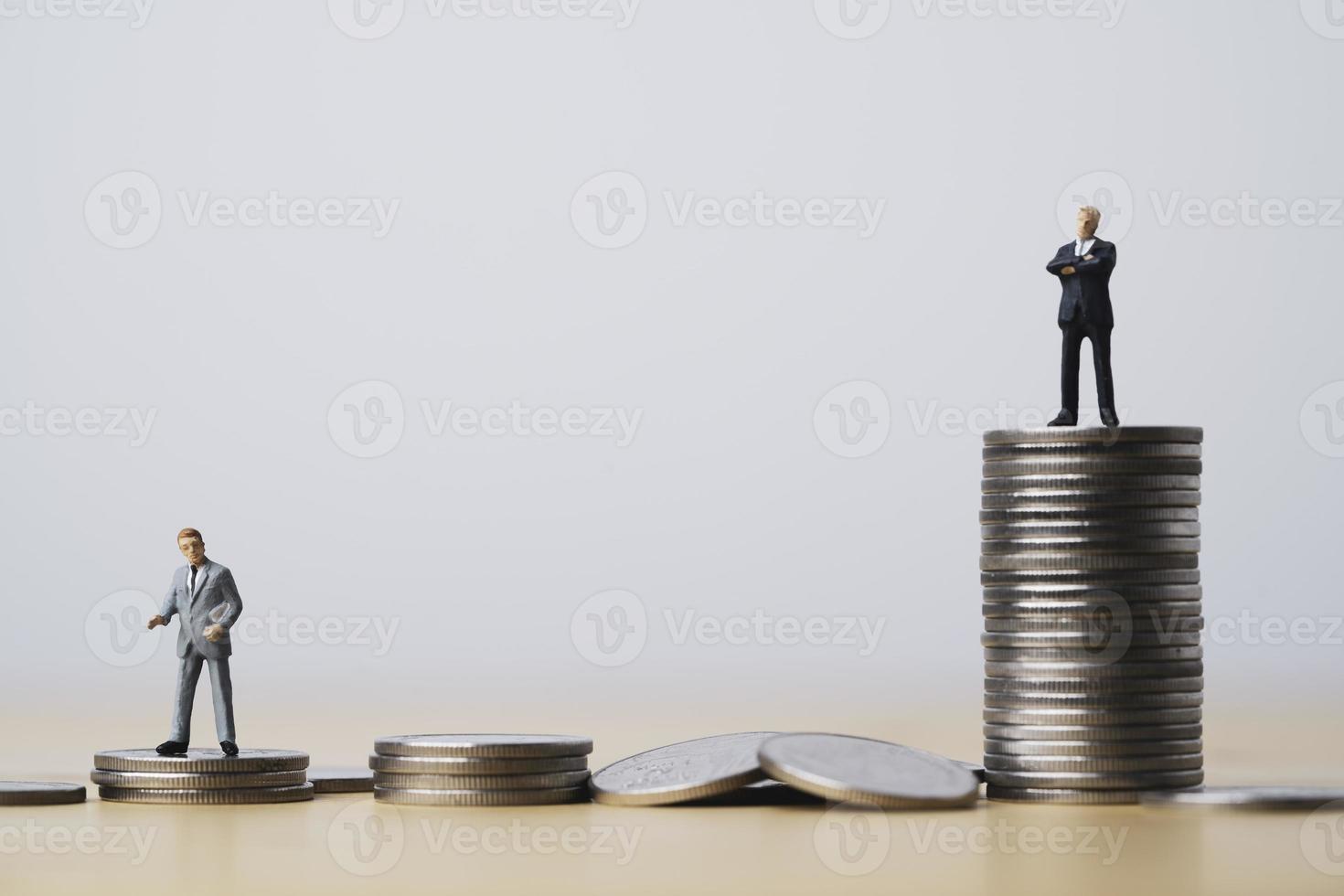 Miniature figure of two businessmen standing to different high and low coins stacking for position and successful business investment income concept. photo