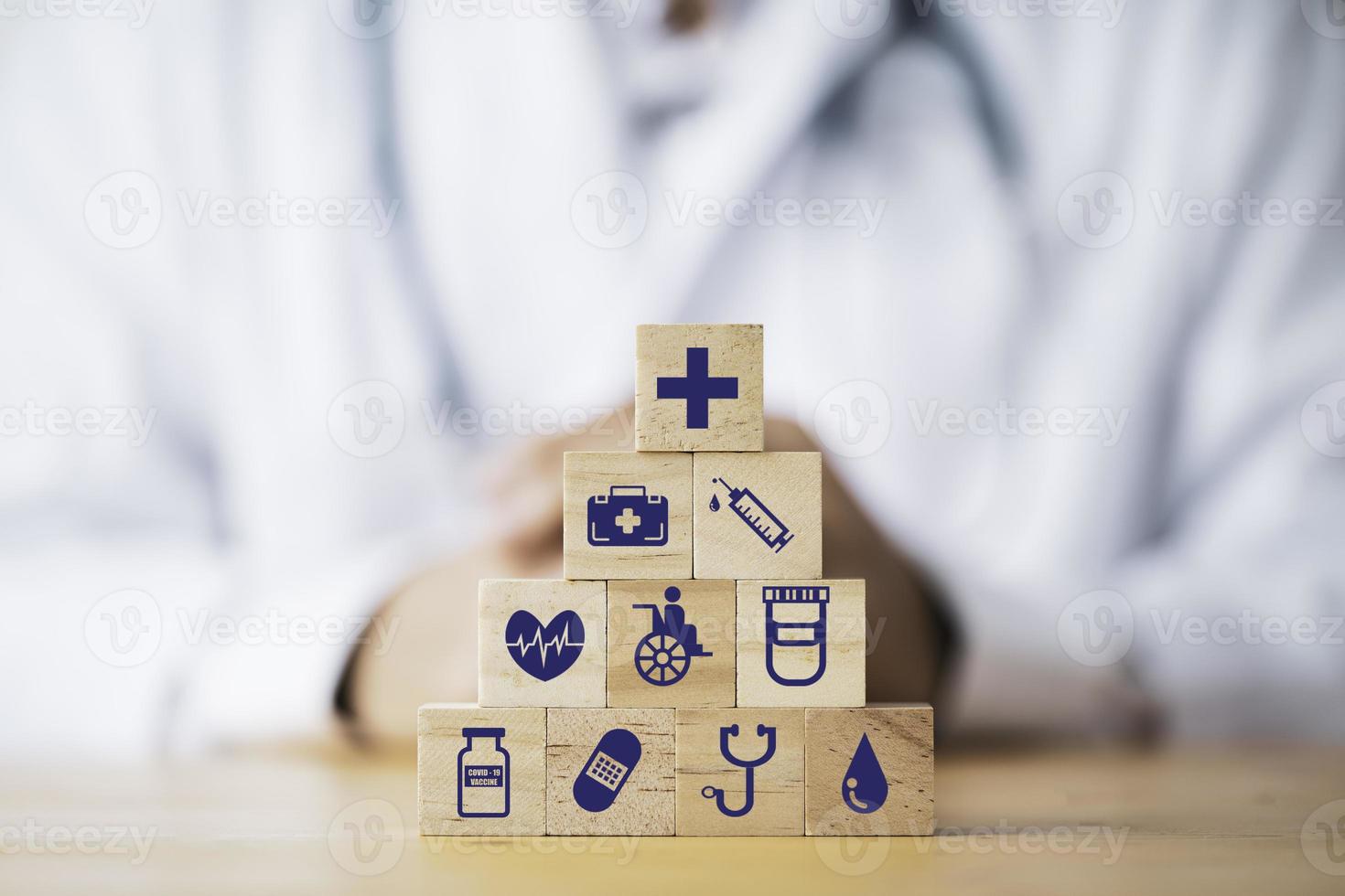 Doctor putting and stacking wooden block cube which print screen health care and medical icons for healthy and wellness concept. photo