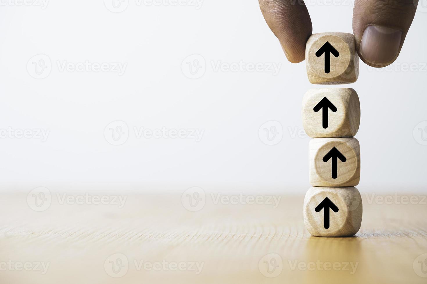 mano colocando o aumentando la flecha que imprime la pantalla en un bloque de cubo de madera para el crecimiento de los beneficios de dividendos y mejora el concepto de inversión. foto