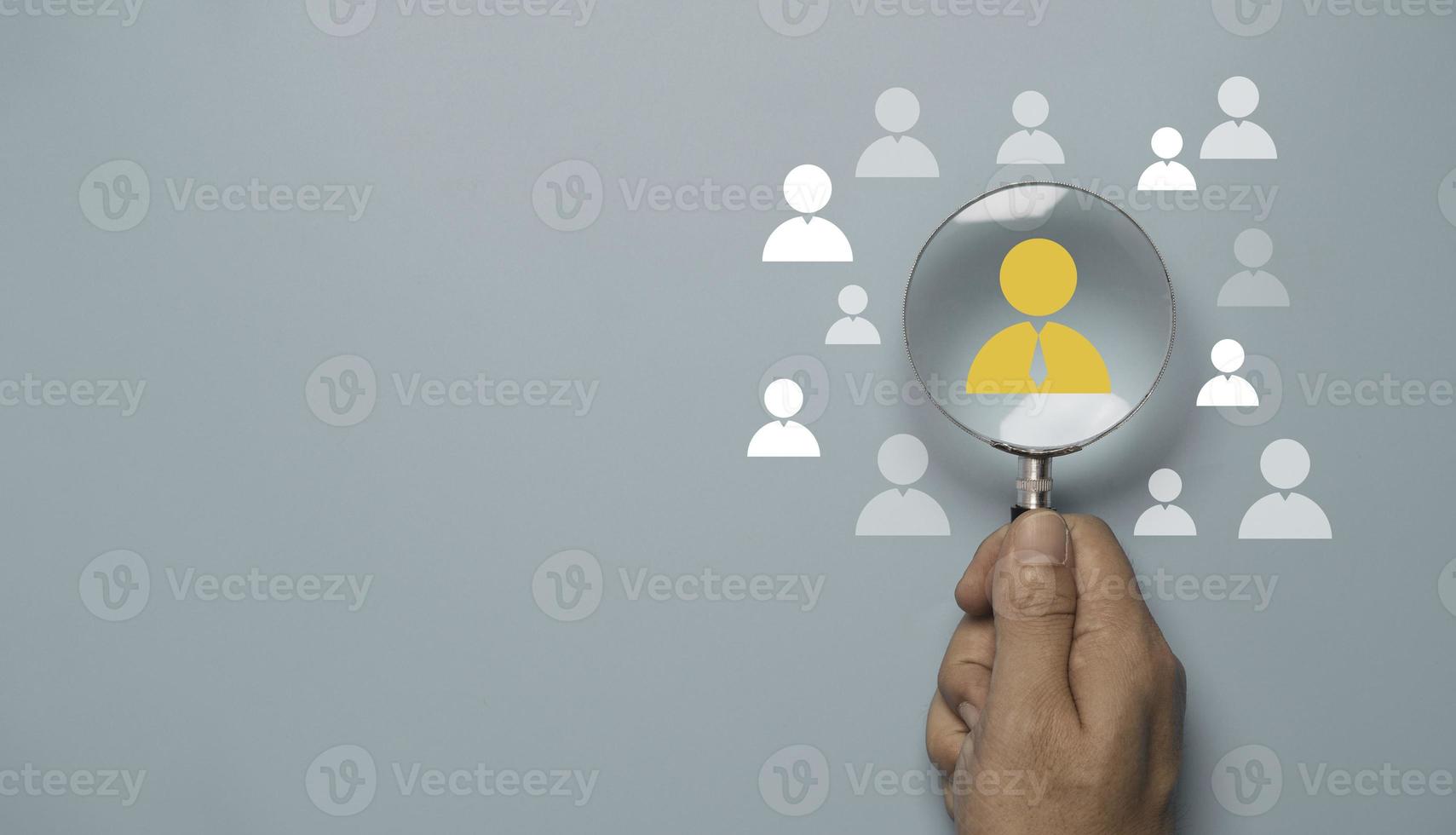 Hand holding magnifier glass and focus to manager icon which is among staff icons for human development recruitment leadership and customer target concept. photo