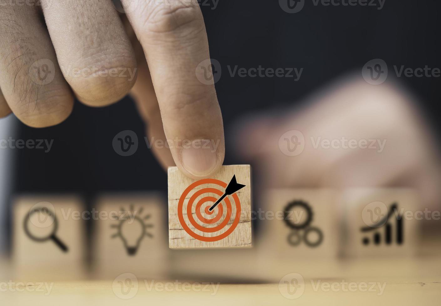 Hand  putting target board which printing on wooden cube block on mechanical gear and lightbulb icon  for creative and set up business objective target  goal concept. photo