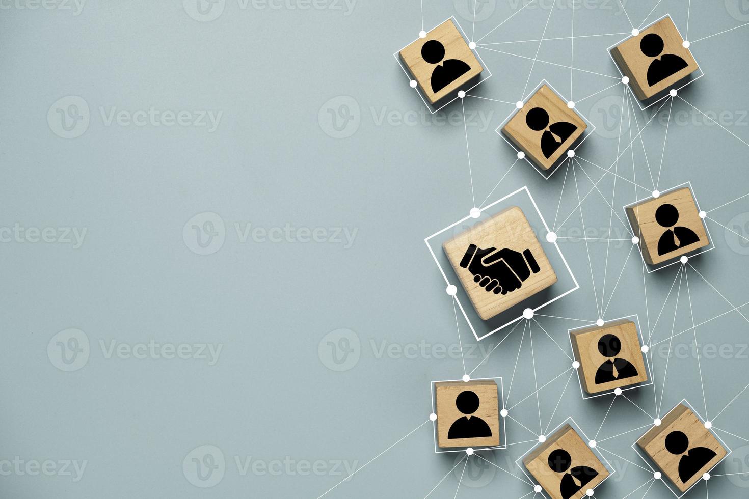 Top view design on blue background of Hand shaking which print screen on wooden cube block which connection with human icon for business deal and agreement concept. photo