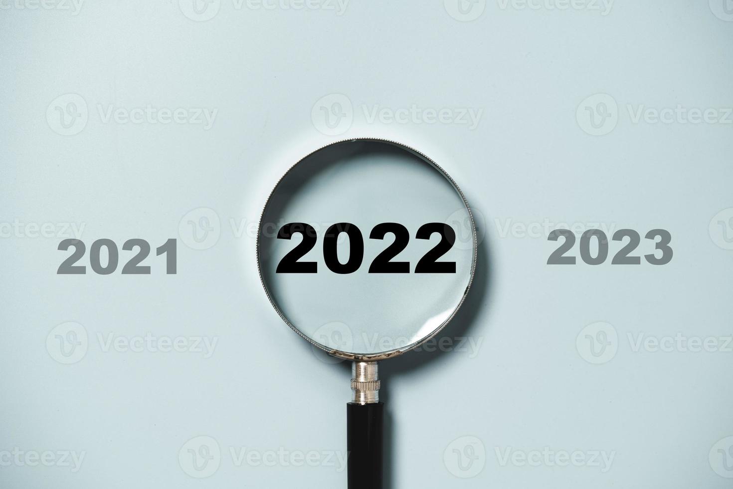 2022 year inside of magnifier glass on blue background for focus on target of new business of starting new year concept. photo