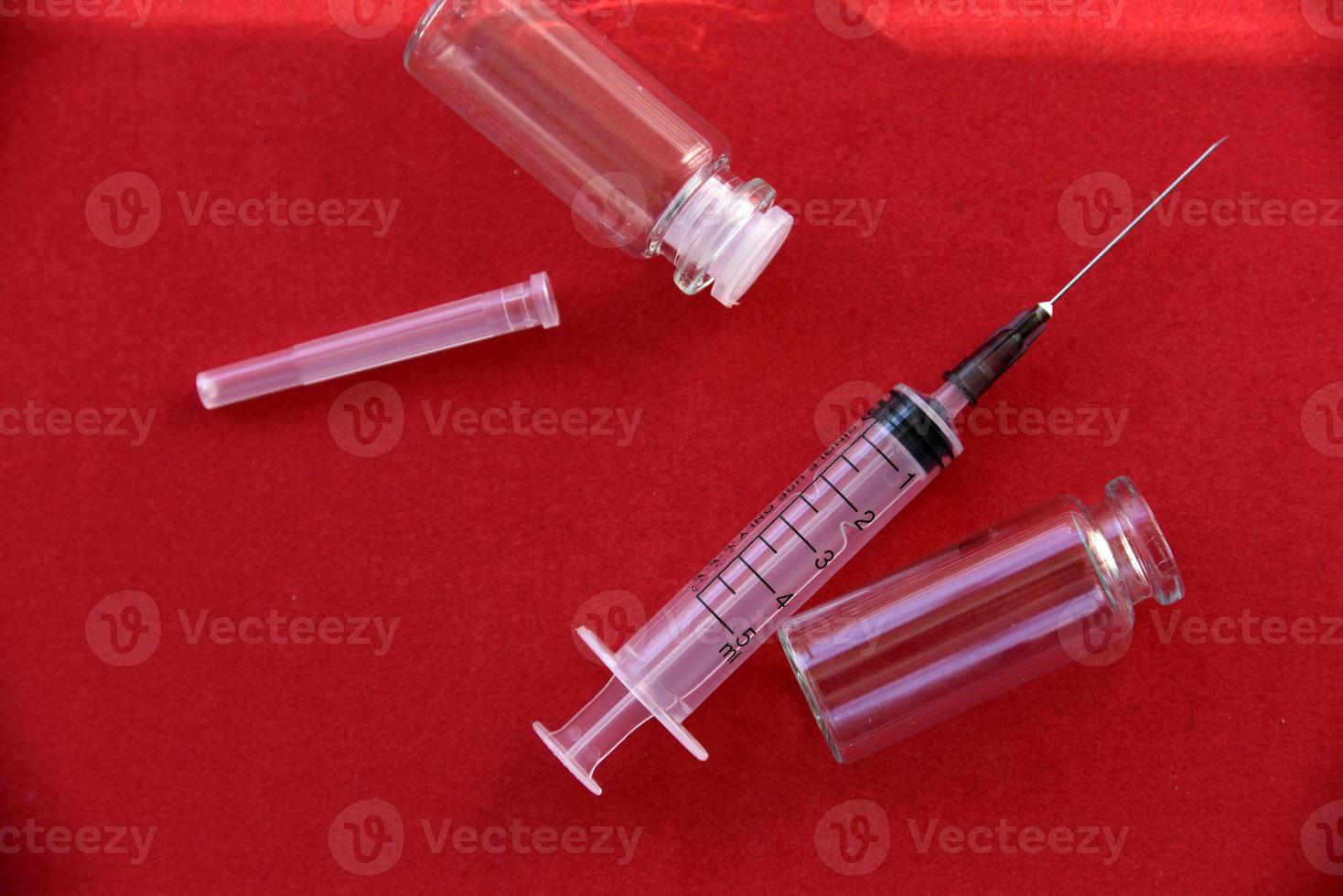 Medical syringe tablets and glass bubbles on a red background photo