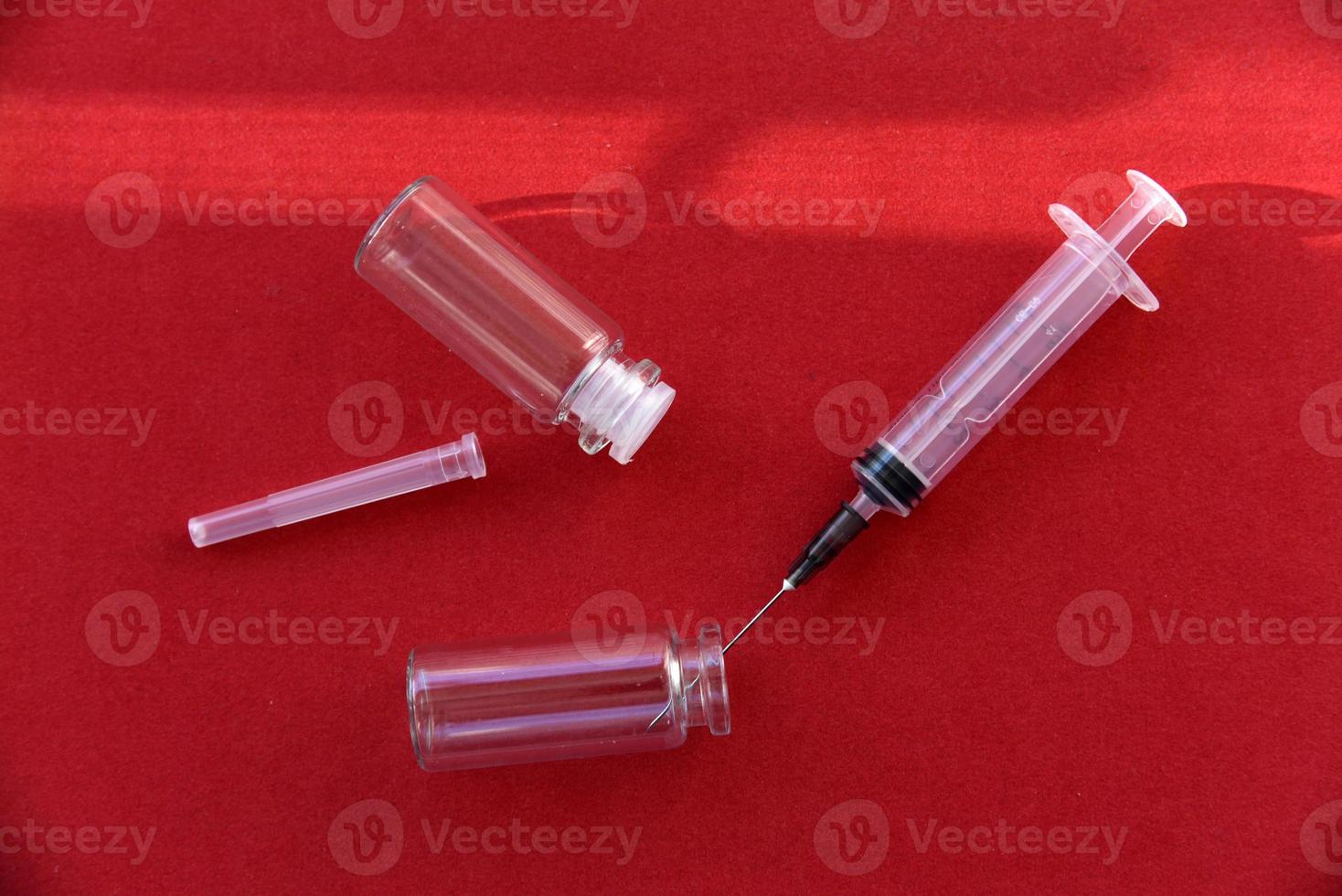 Medical syringe tablets and glass bubbles on a red background photo