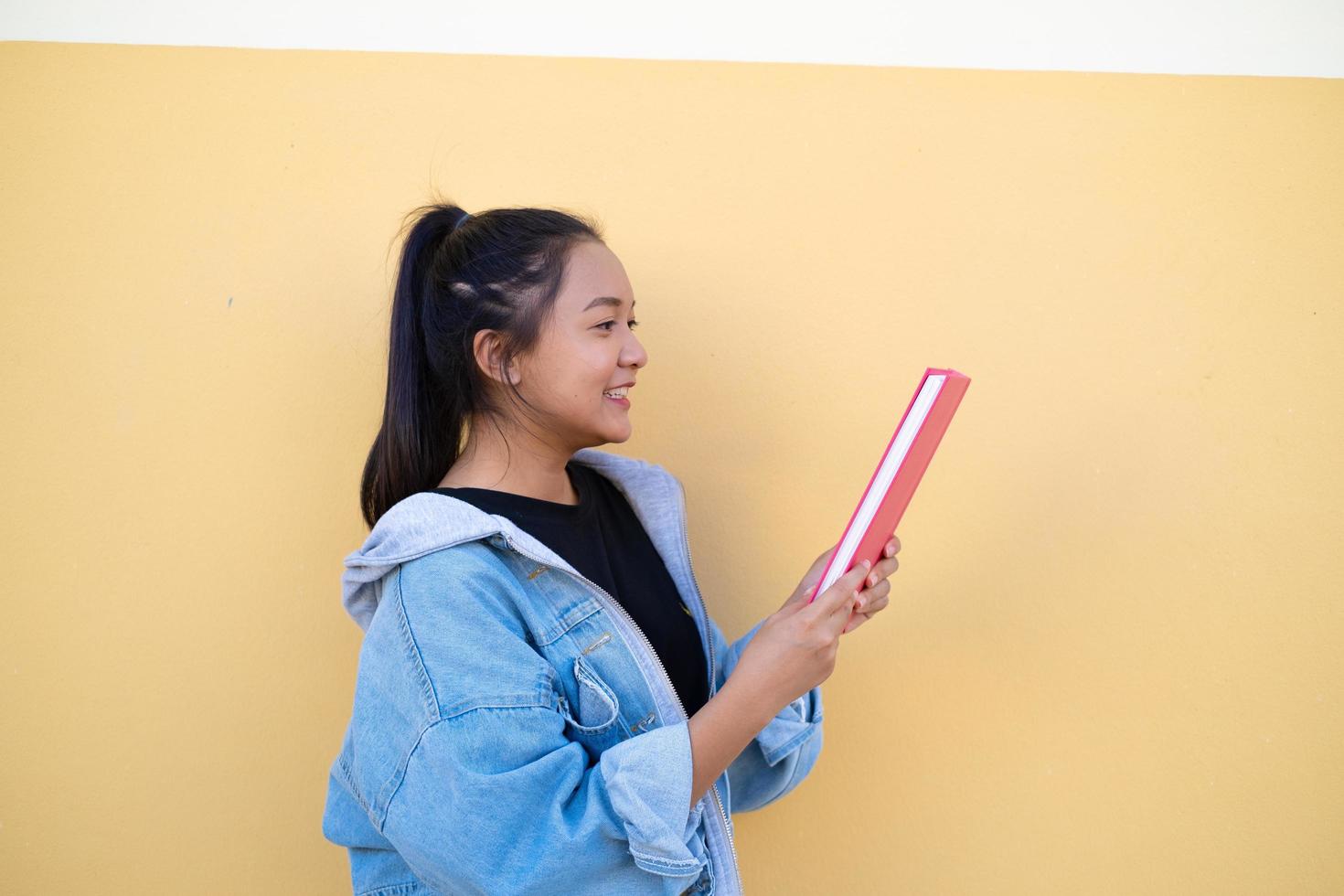 joven estudiante feliz con libro rosa sobre fondo marrón. foto