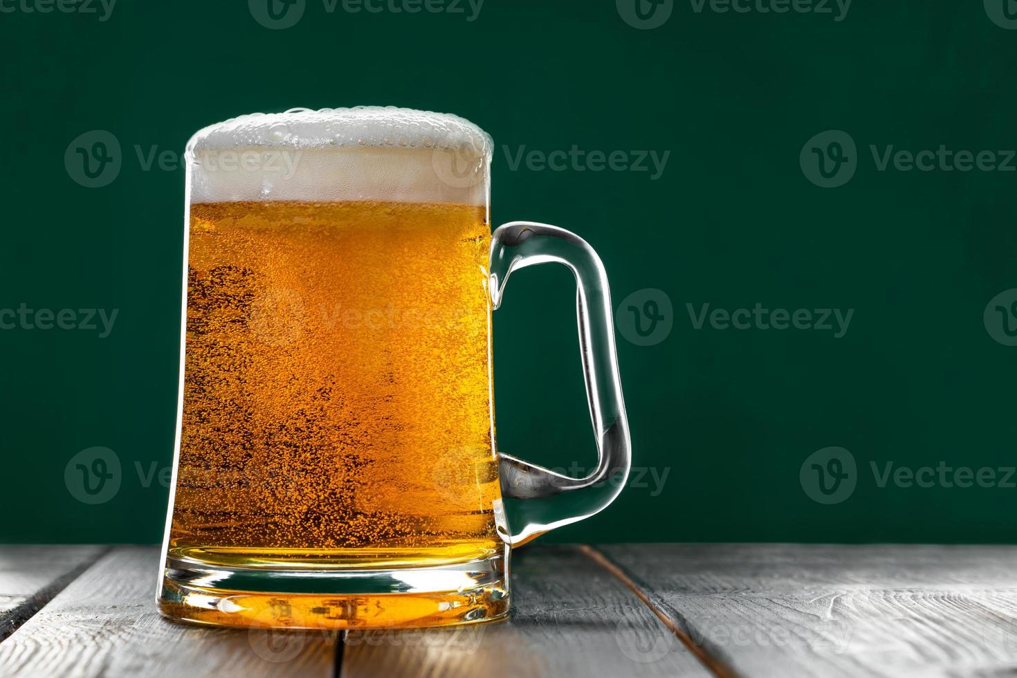 Mug of light beer with foam on a green background. Traditional Irish drink. photo