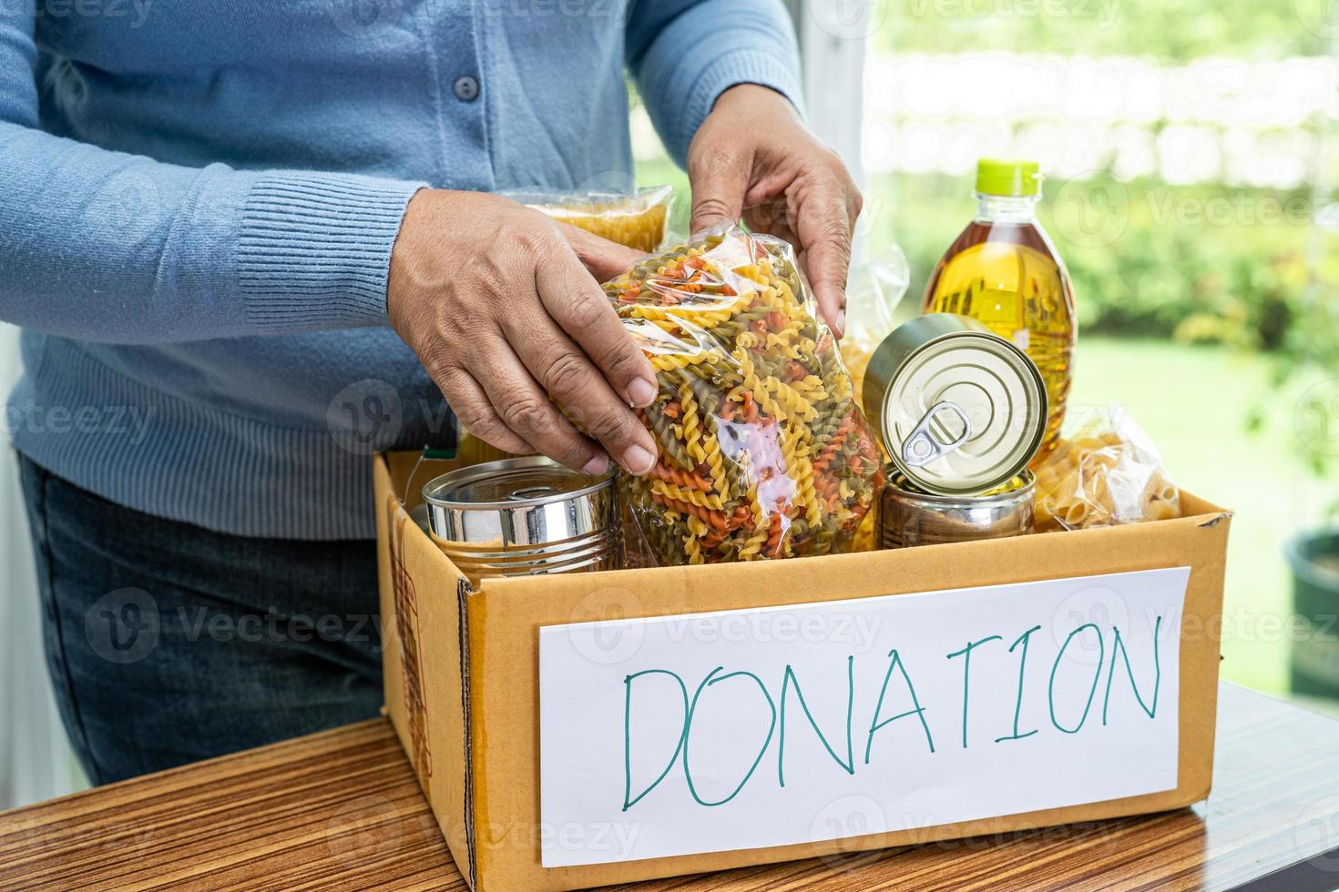 Volunteers putting various dry food in donation box for help people. photo