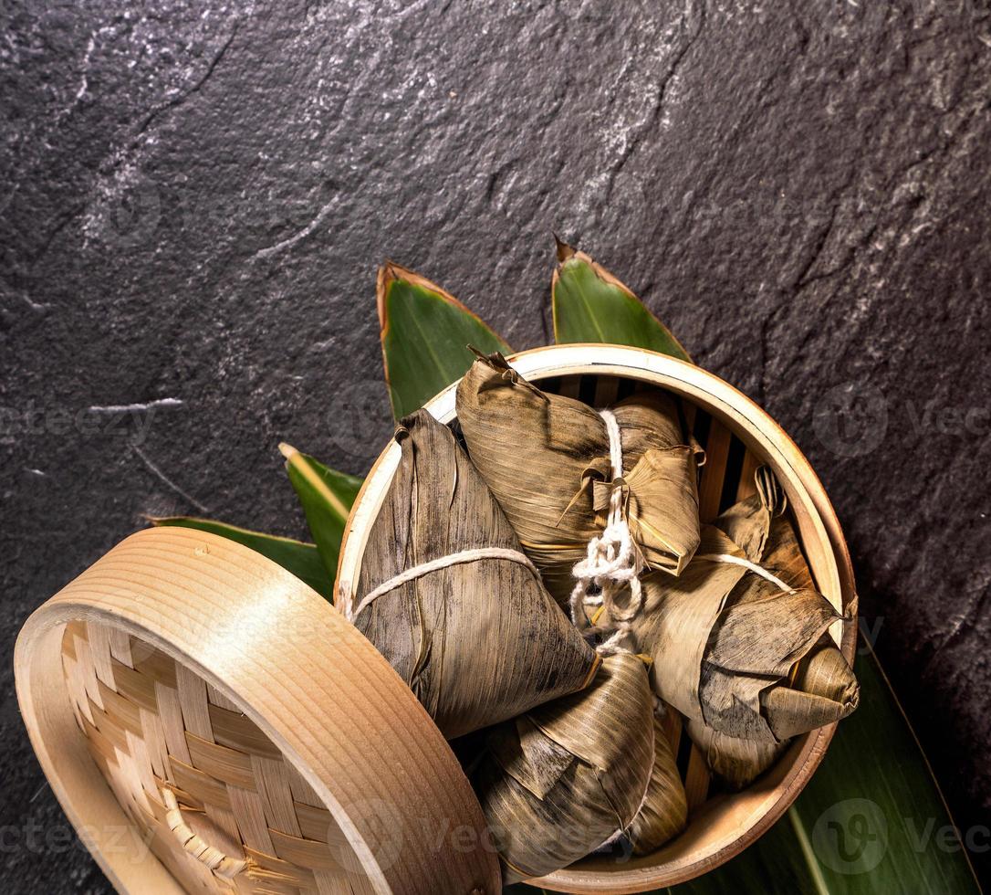 Close up, copy space, top view, flat lay. Famous asian chinese tasty handmade food in duan wu event, steamed rice dumplings shaped like pyramidal ingredient on black slate photo