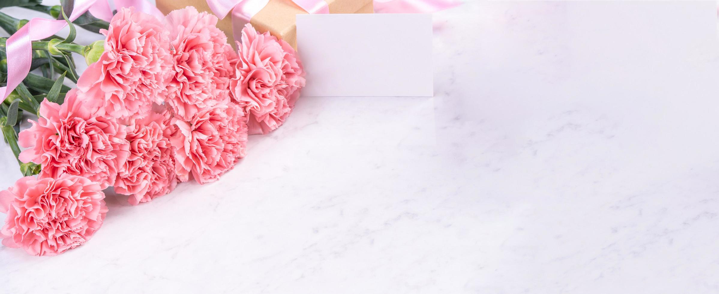 Design concept - Beautiful bunch of carnations on marble white background, top view, copy space, close up, mock up. Mothers day gift idea inspiration. photo