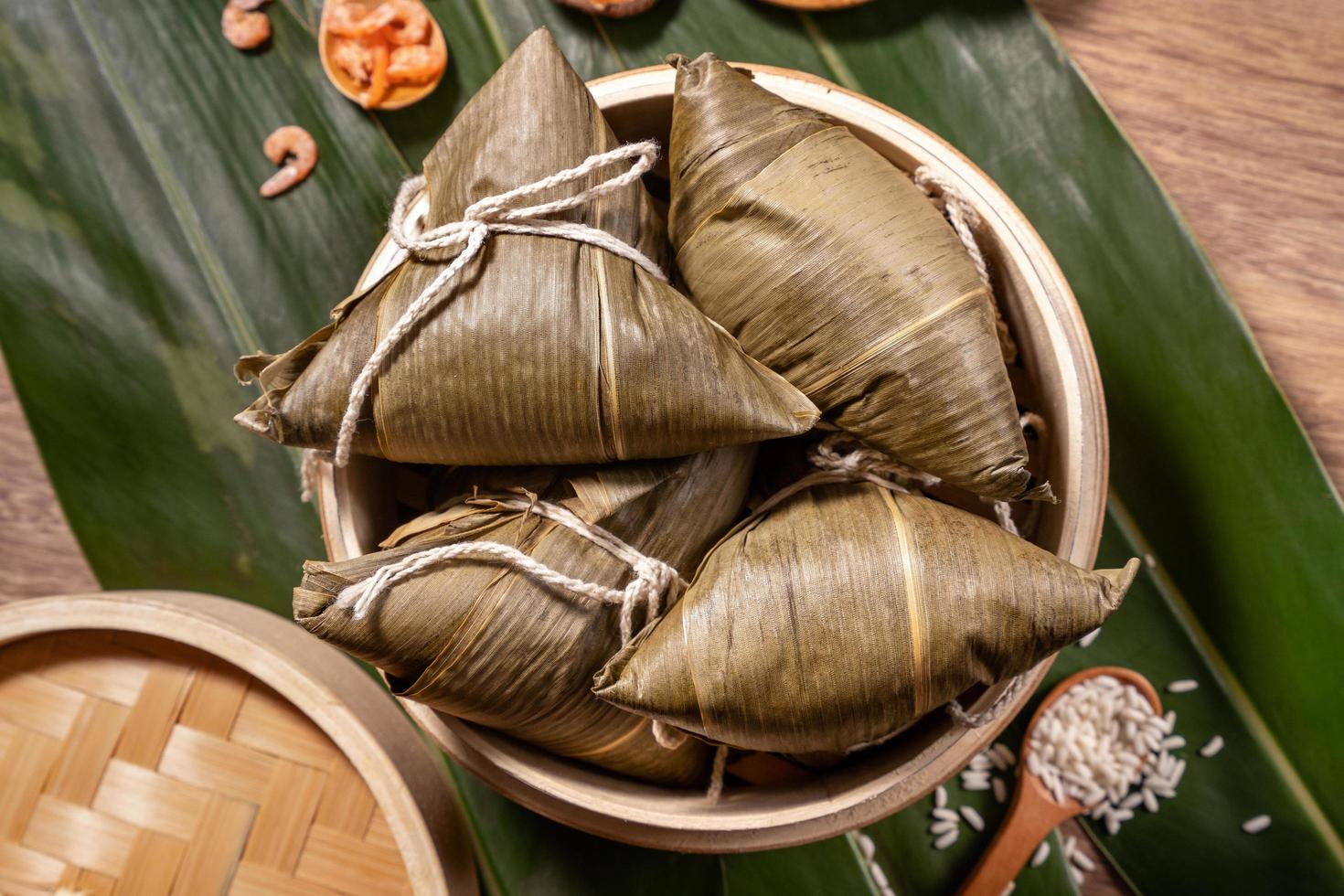 Zongzi, steamed rice dumplings on wooden table bamboo leaves, food in dragon boat festival duanwu concept, close up, copy space, top view, flat lay photo