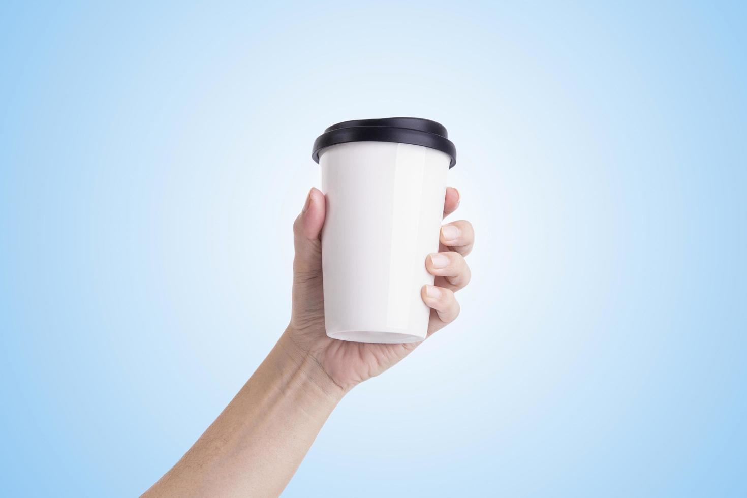 mano masculina sosteniendo una taza de café con leche aislada en un fondo azul claro. foto