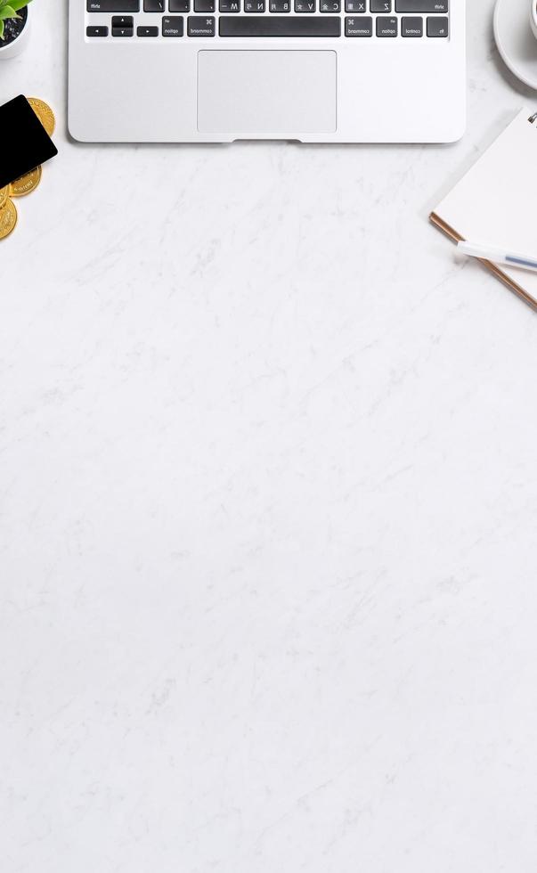 Business financial design concept, marble white office table desk top view with smart phone, mockup credit card, coins, laptop, flat lay, copy space photo