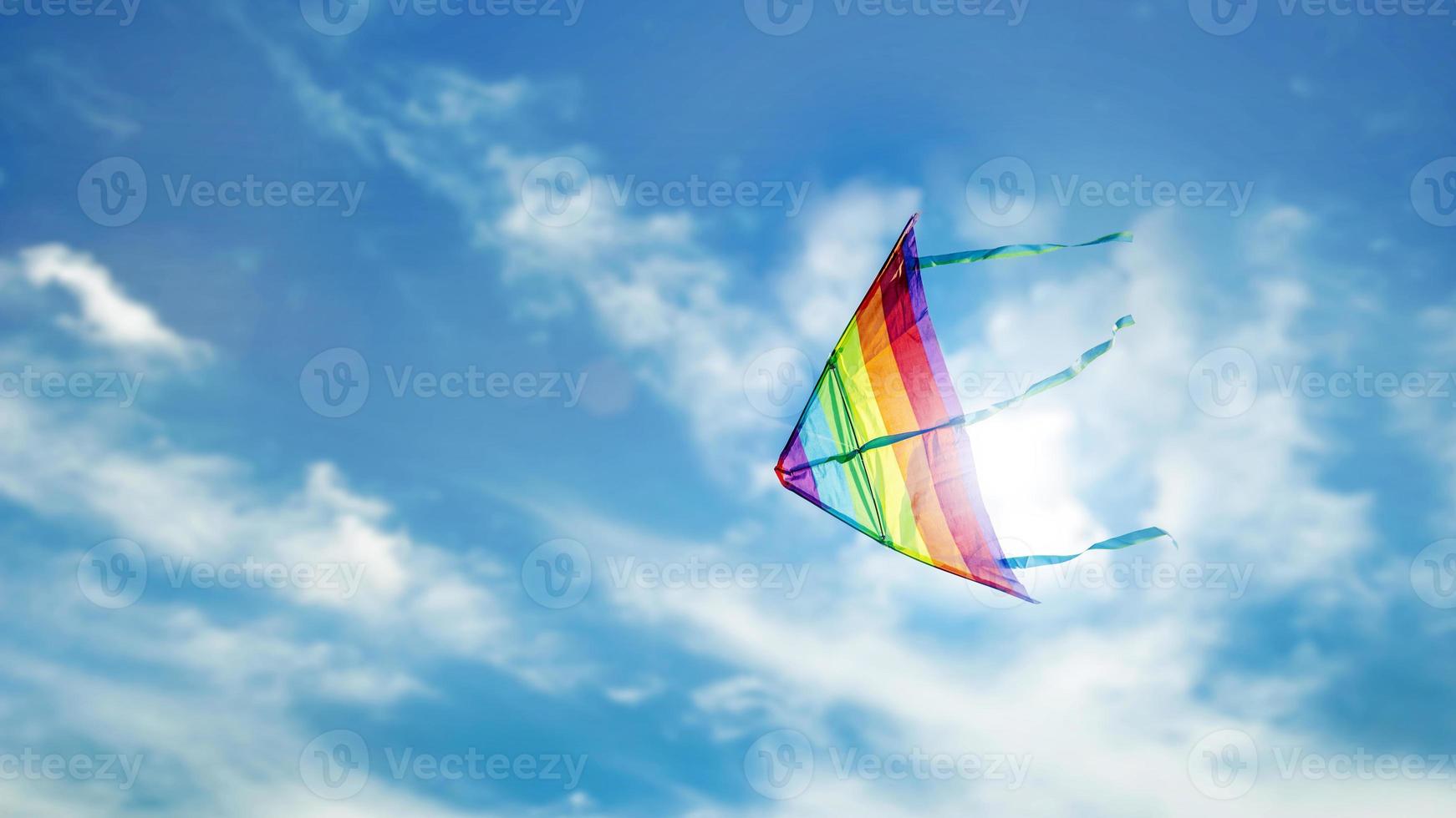 cometa arcoiris volando en el cielo azul con nubes foto