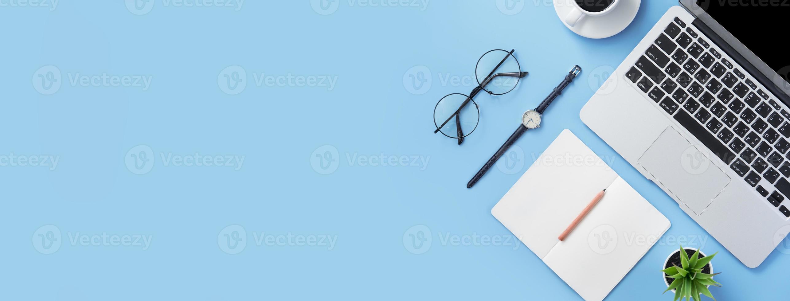 Girl write on open white book or accounting on a minimal clean light blue desk with laptop and accessories, copy space, flat lay, top view, mock up photo