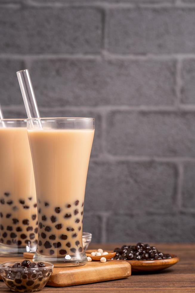 Delicious bubble milk tea with straw in drinking glass on wooden table background, concept of reduce plastic to go in Taiwan, close up, copy space photo