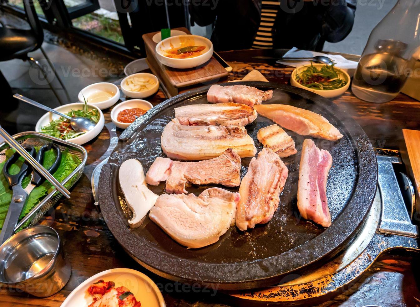 comida de cerdo negro cocida a la sartén en el restaurante de Corea, deliciosa cocina coreana fresca en placa de hierro con lechuga, primer plano, espacio para copiar, estilo de vida foto