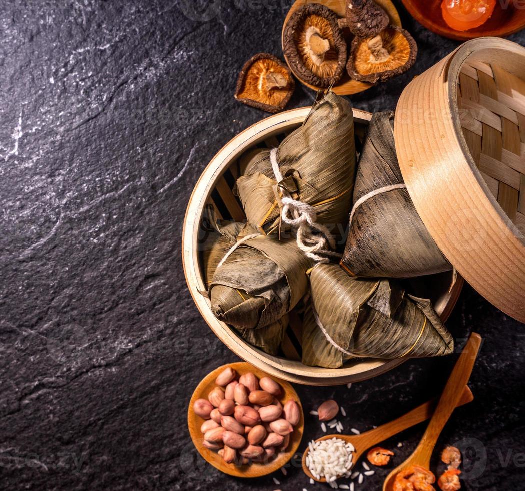 Close up, copy space, top view, flat lay. Famous asian chinese tasty handmade food in duan wu event, steamed rice dumplings shaped like pyramidal ingredient on black slate photo