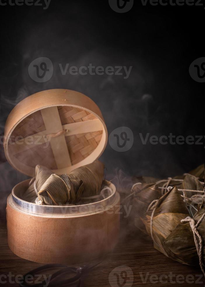 Zongzi, steamed rice dumplings in steamer on wooden table, famous tasty food in dragon boat festival duanwu design concept, close up, copy space. photo