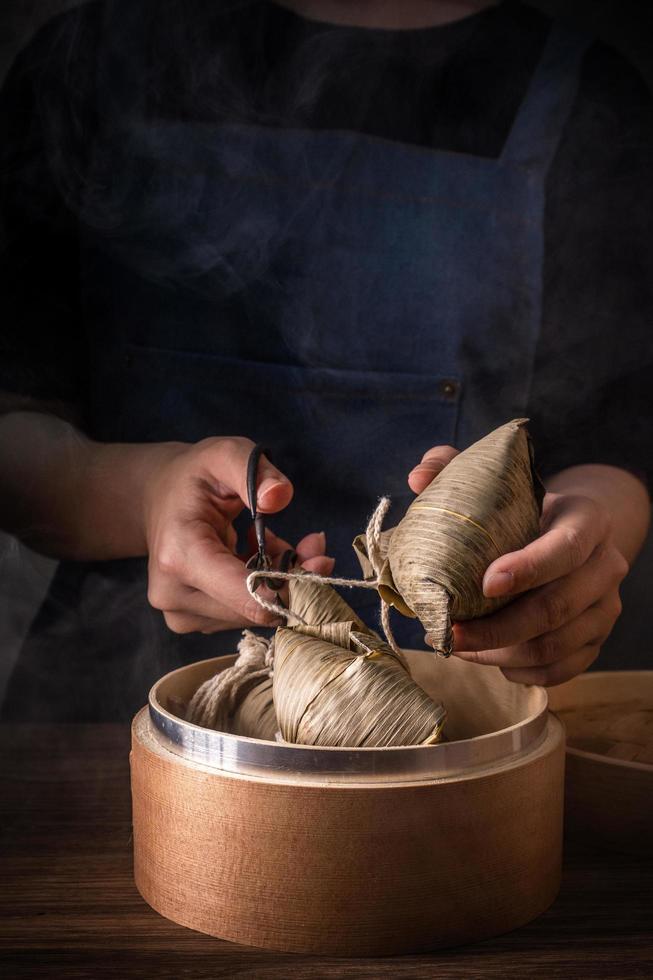 zongzi, mujer que va a comer albóndigas de arroz al vapor en una mesa de madera, famosa comida sabrosa en el concepto de diseño duanwu del festival del bote del dragón, primer plano, espacio de copia foto