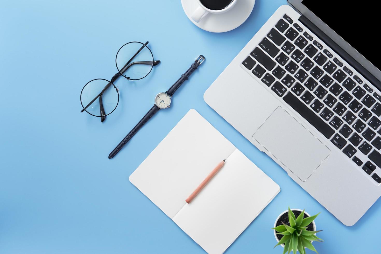 Girl write on open white book or accounting on a minimal clean light blue desk with laptop and accessories, copy space, flat lay, top view, mock up photo