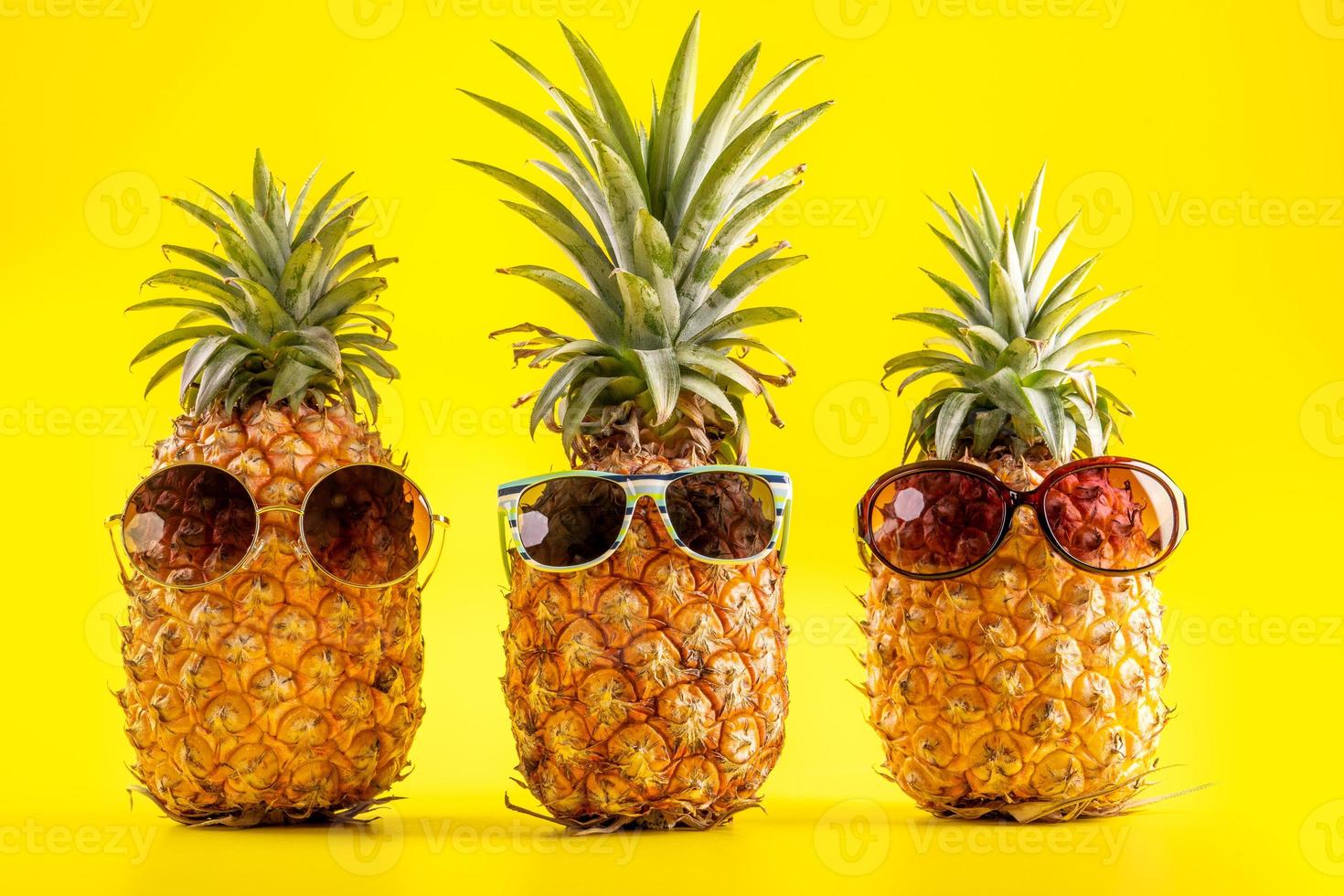 Creative pineapple looking up with sunglasses and shell isolated on yellow background, summer vacation beach idea design pattern, copy space close up photo