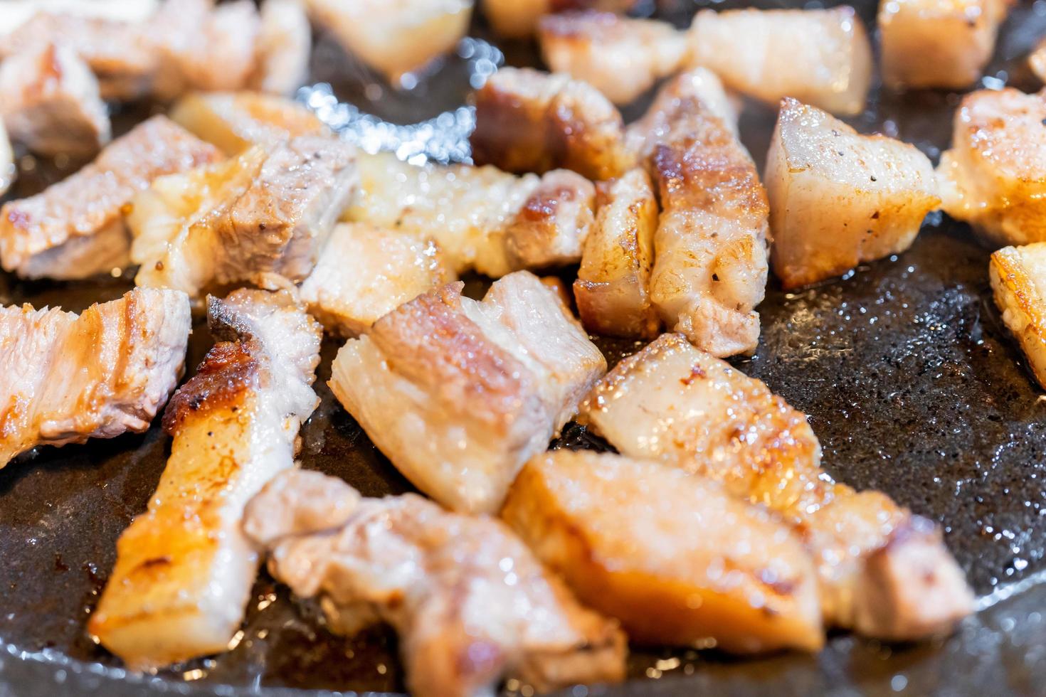 Pan-fried cooked black pork meal in Korea restaurant, fresh delicious korean food cuisine on iron plate with lettuce, close up, copy space, lifestyle photo