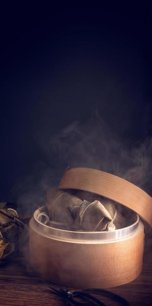 Zongzi, steamed rice dumplings in steamer on wooden table, famous tasty food in dragon boat festival duanwu design concept, close up, copy space. photo