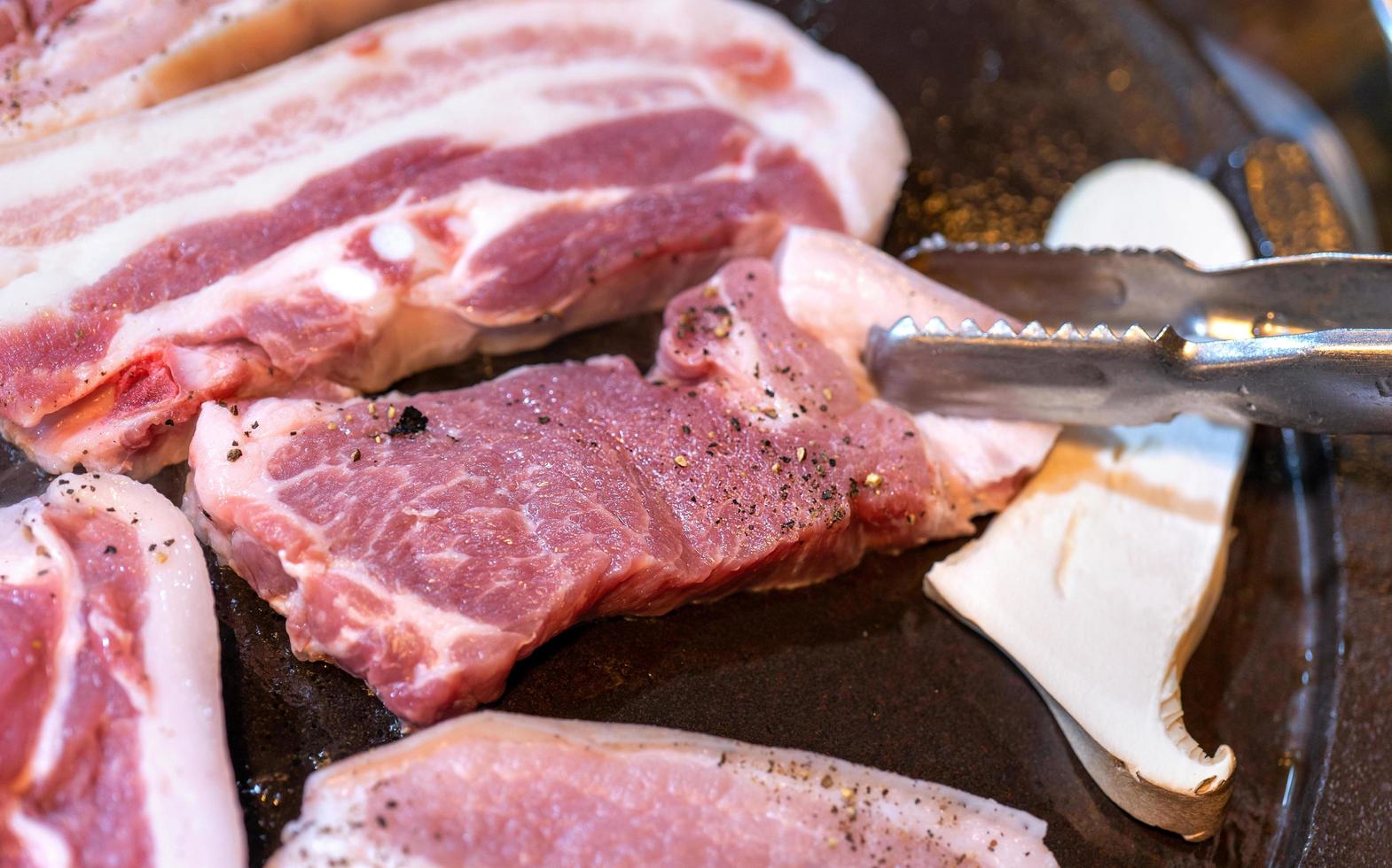 Pan-fried black pork meal in Korea restaurant, fresh delicious korean food cuisine on iron plate with lettuce, close up, copy space, lifestyle photo