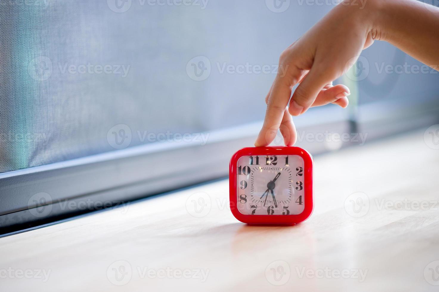 Hand and red alarm clock that shows the alarm at all Every morning, the concept of punctuality photo