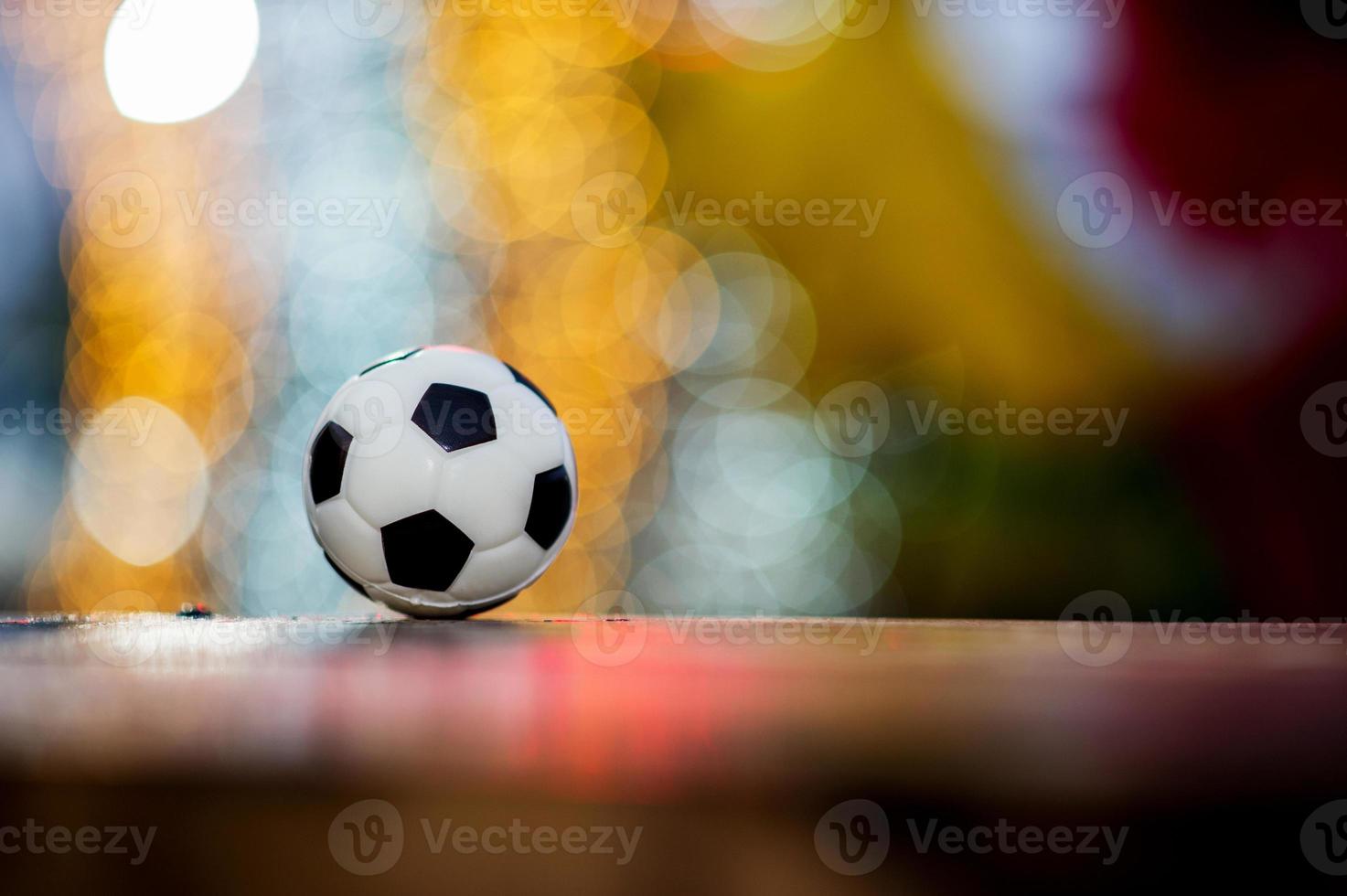 el balón de fútbol se coloca sobre un suelo de madera y tiene un fondo borroso con un hermoso bokeh. foto