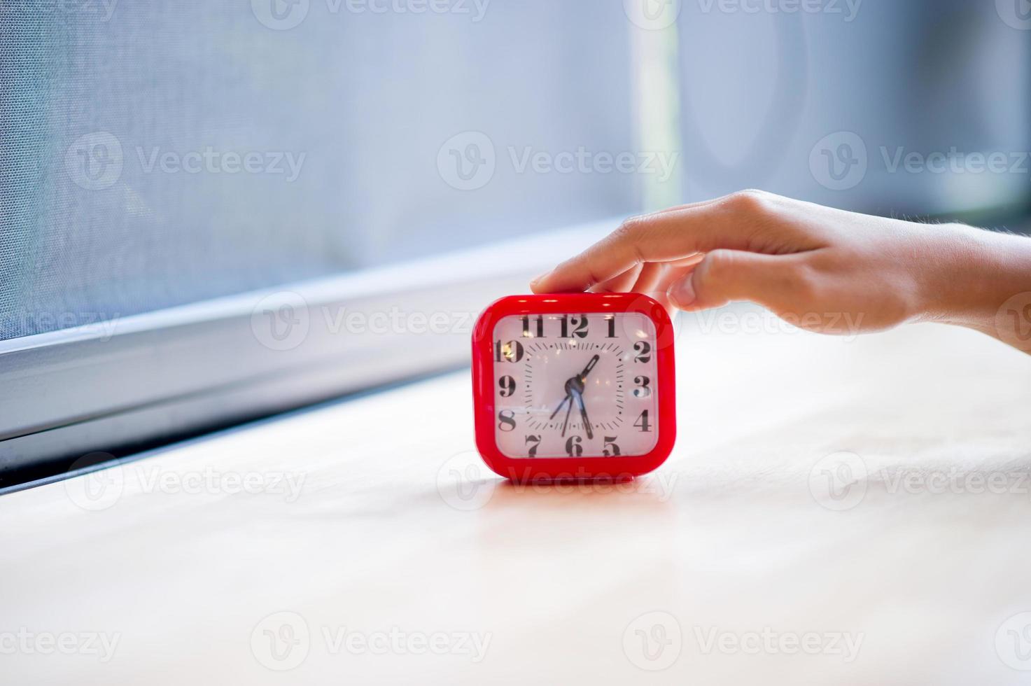 Hand and red alarm clock that shows the alarm at all Every morning, the concept of punctuality photo