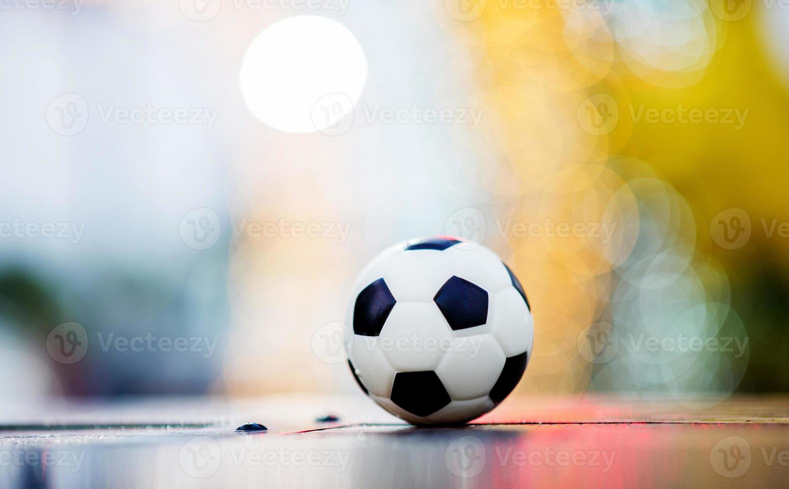 el balón de fútbol se coloca sobre un suelo de madera y tiene un fondo borroso con un hermoso bokeh. foto