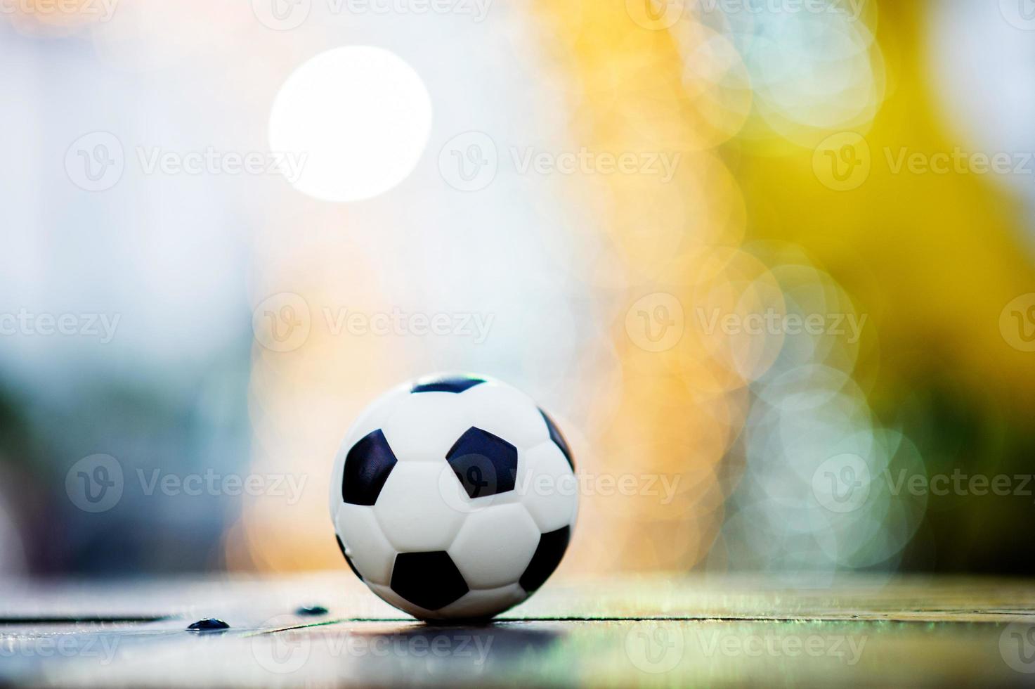 The soccer ball is placed on a wooden floor and has a blurred background with beautiful bokeh. photo