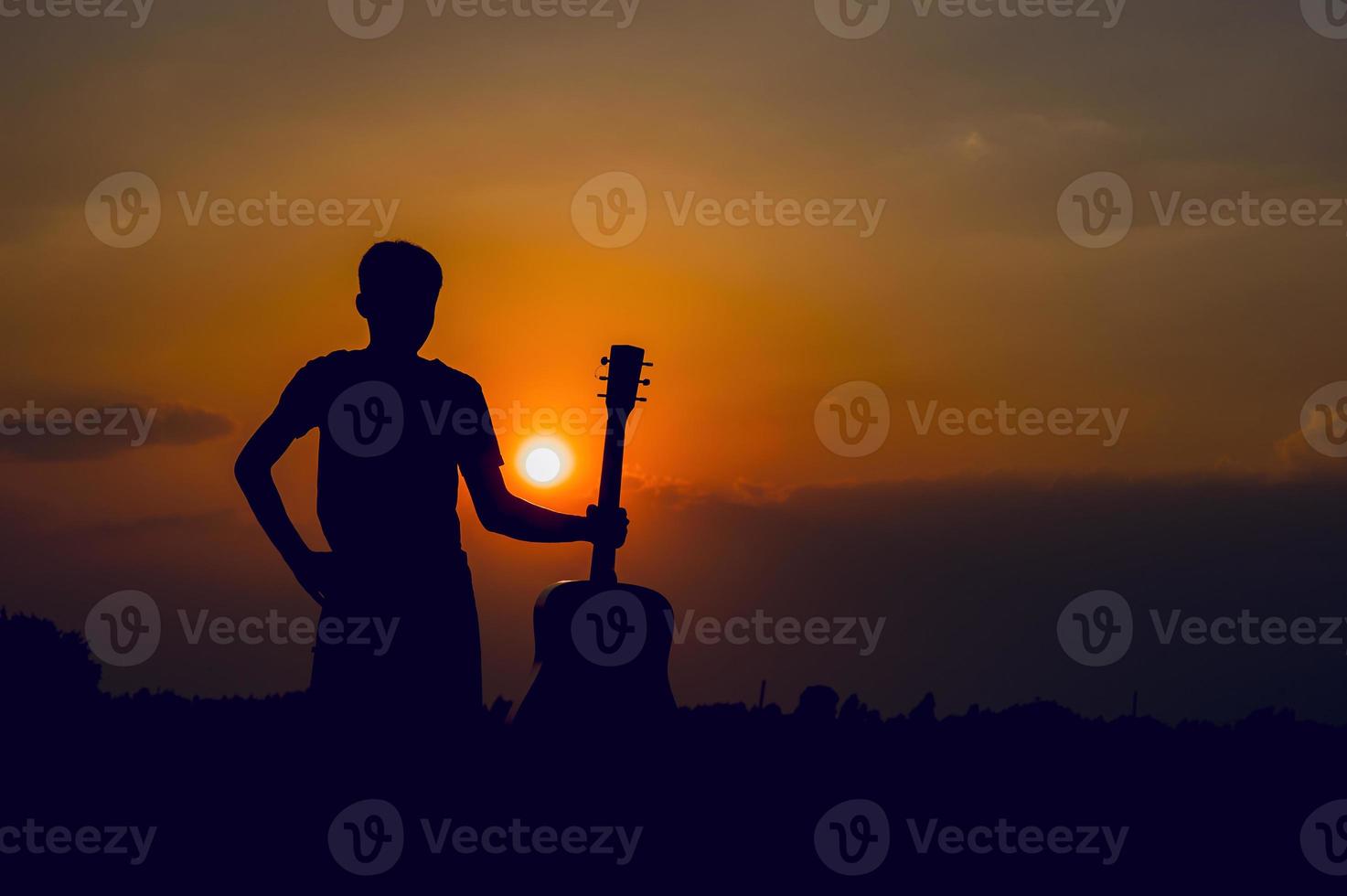 The silhouette of a guitarist who holds a guitar and has a sunset, silhouette concept. photo