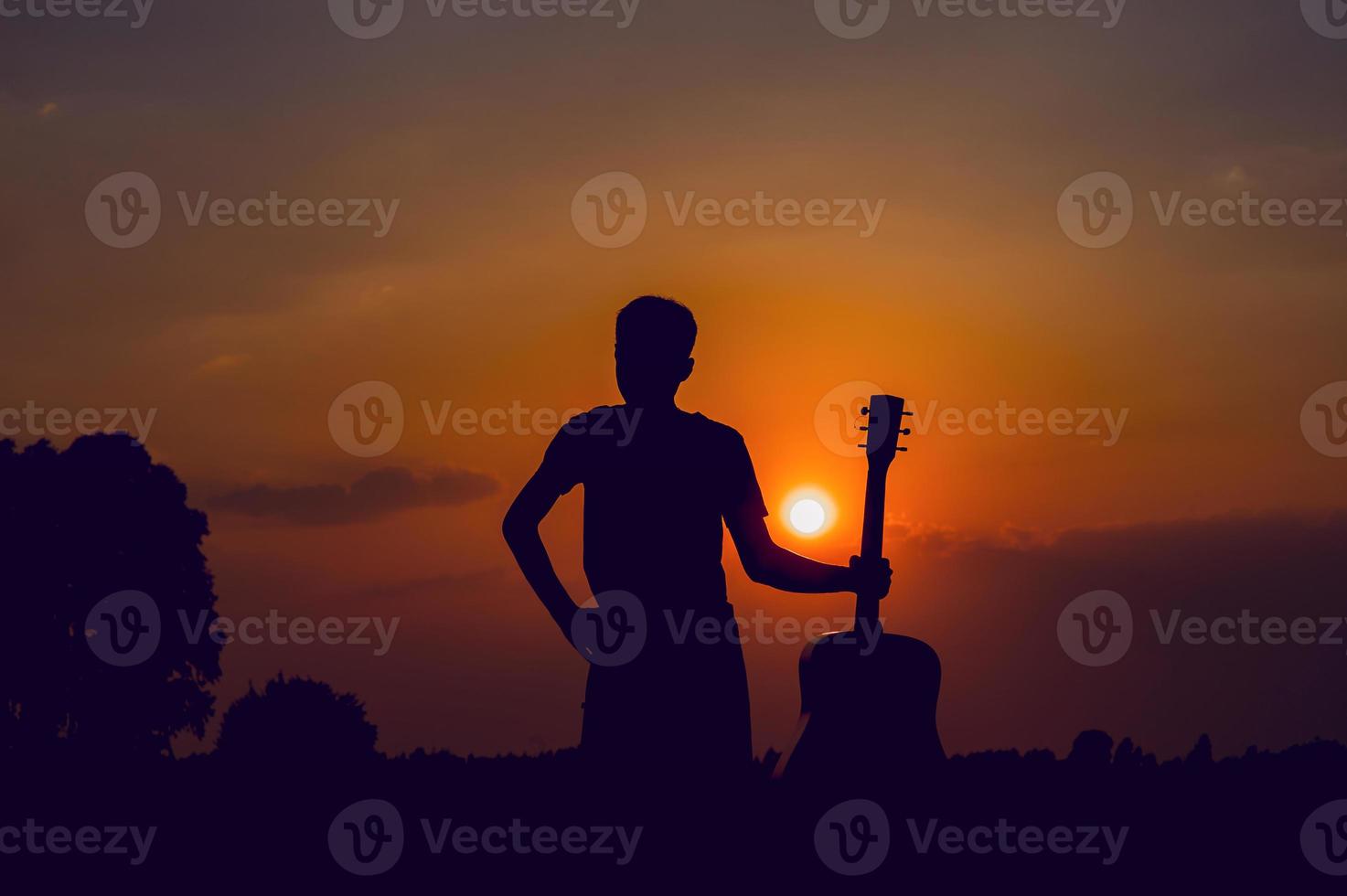 The silhouette of a guitarist who holds a guitar and has a sunset, silhouette concept. photo