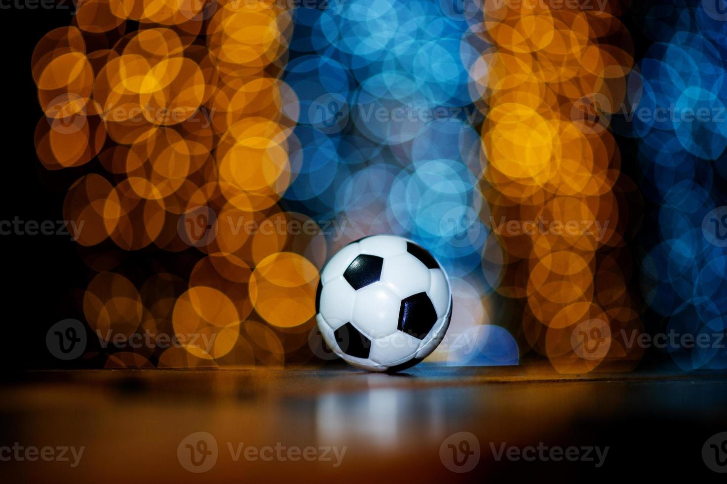 la pelota de fútbol blanca se coloca sobre un trozo de madera y tiene un hermoso fondo bokeh. foto