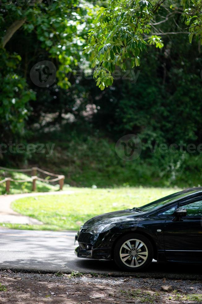 A black car parked by the side of the forest photo