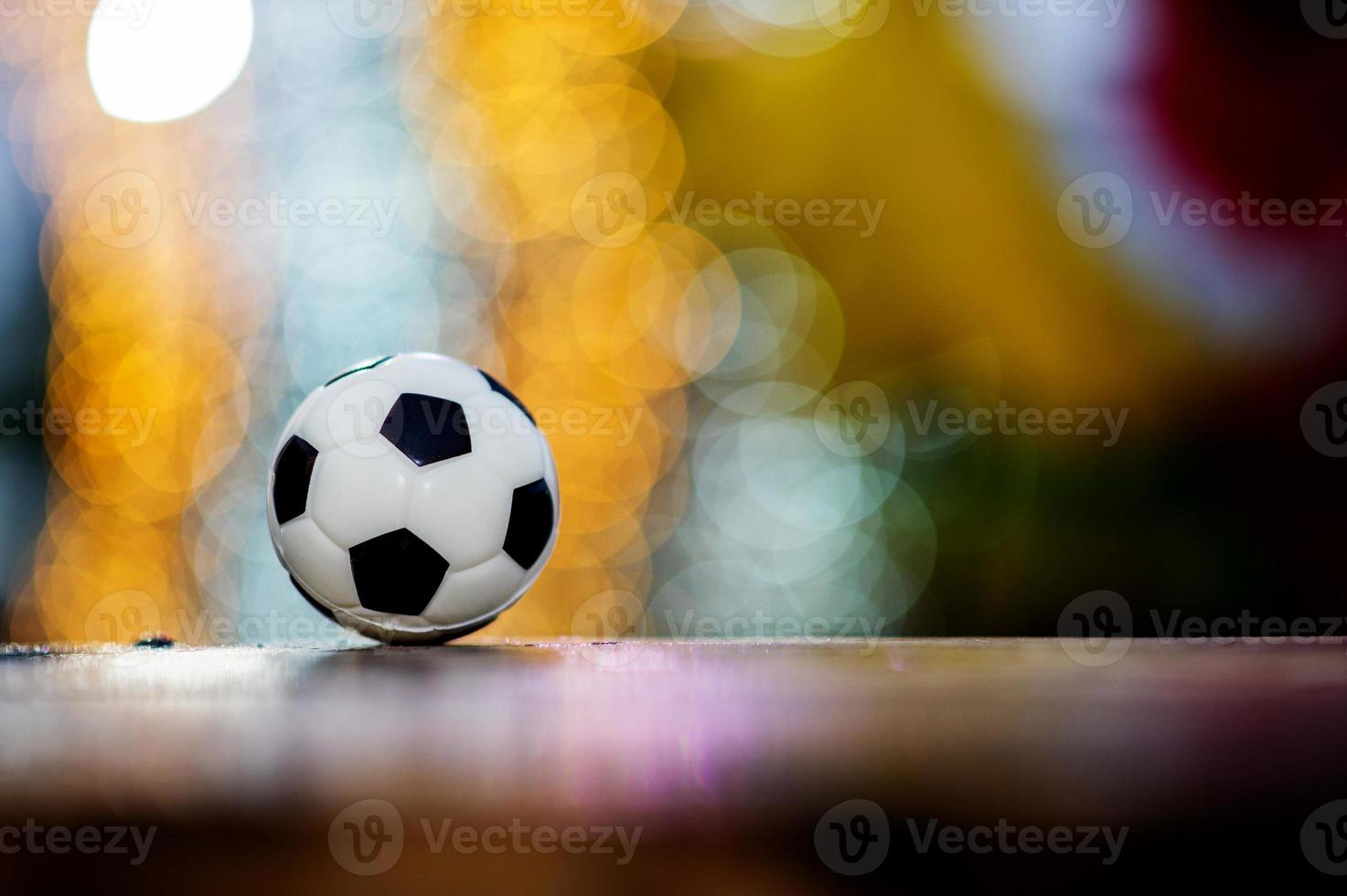 The soccer ball is placed on a wooden floor and has a blurred background with beautiful bokeh. photo