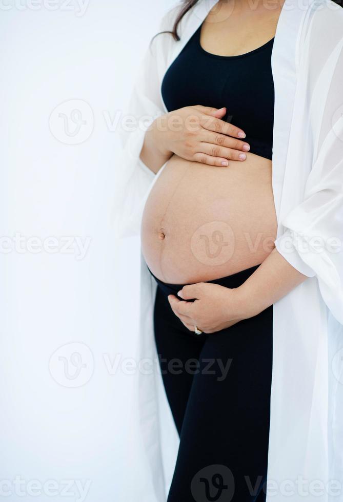 la mujer embarazada está embarazada de una habitación blanca. foto