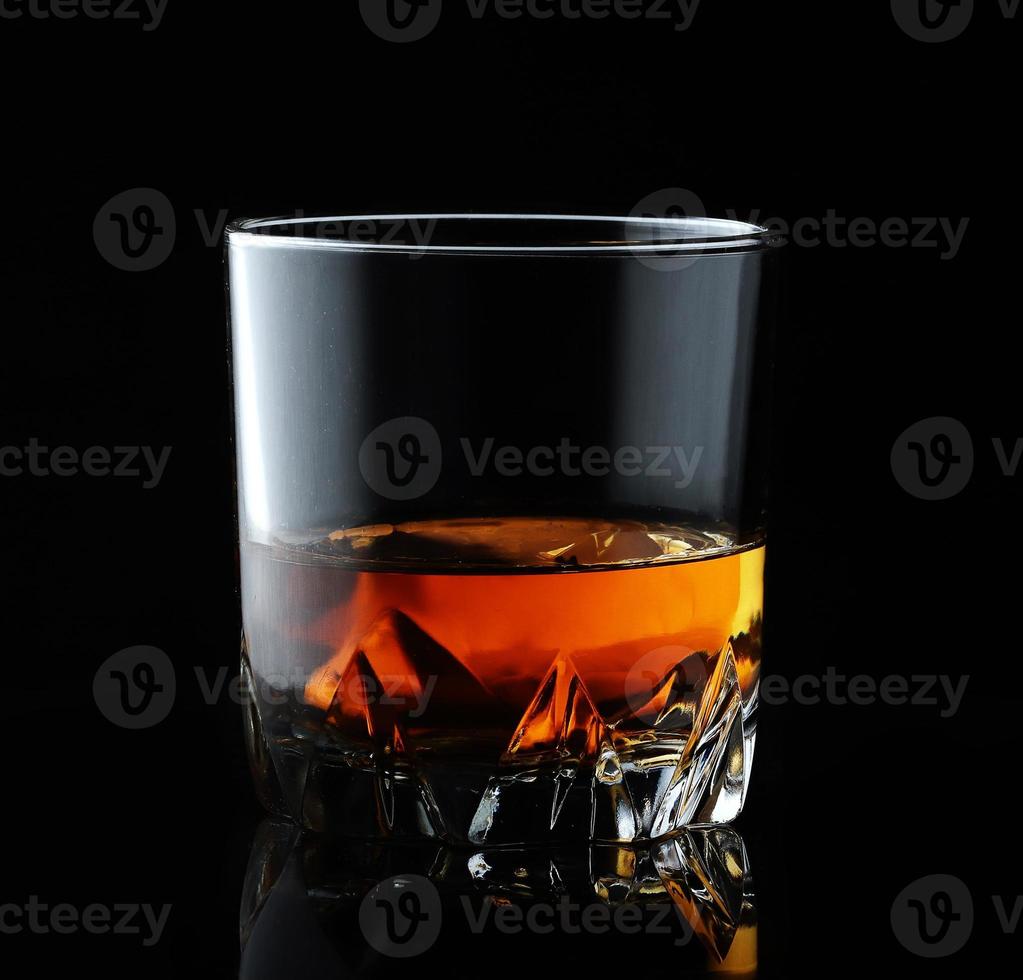 Scotch whiskey in an elegant glass on a black background with reflections. photo