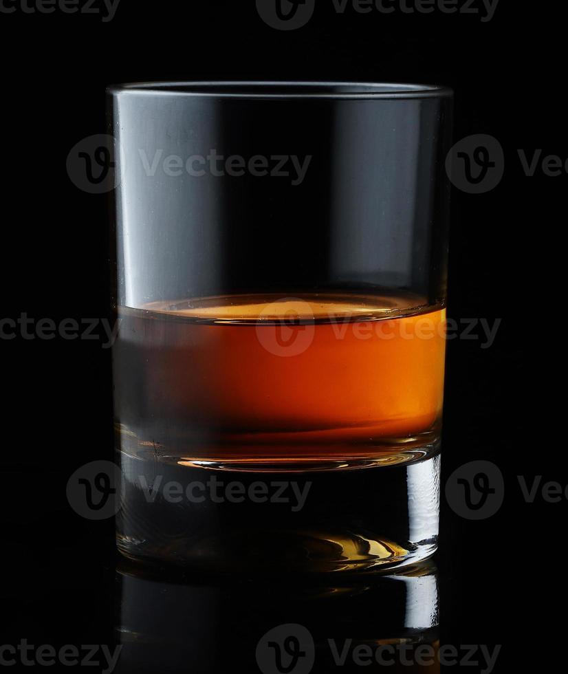 Scotch whiskey in an elegant glass on a black background with reflections. photo
