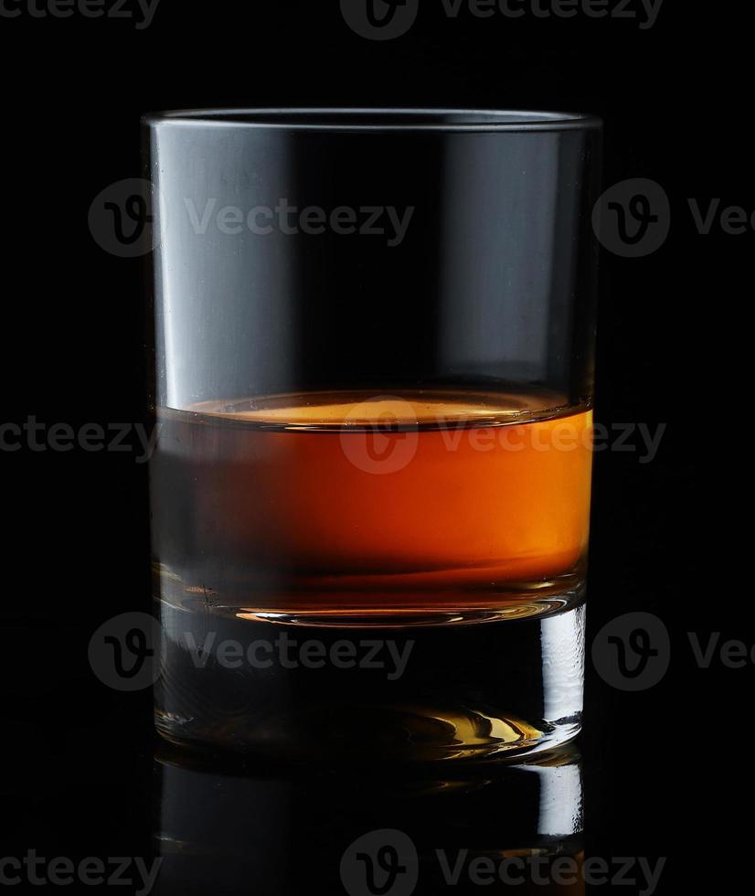 whisky escocés en un vaso elegante sobre un fondo negro con reflejos. foto