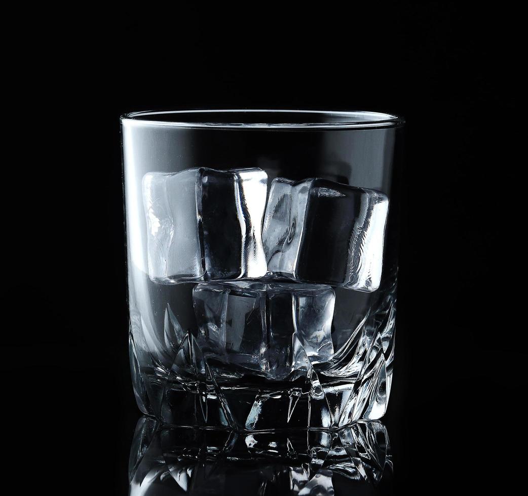 Ice cubes in empty glass on black background. Glass of water or whiskey and wine. Empty glass for alcoholic beverages photo