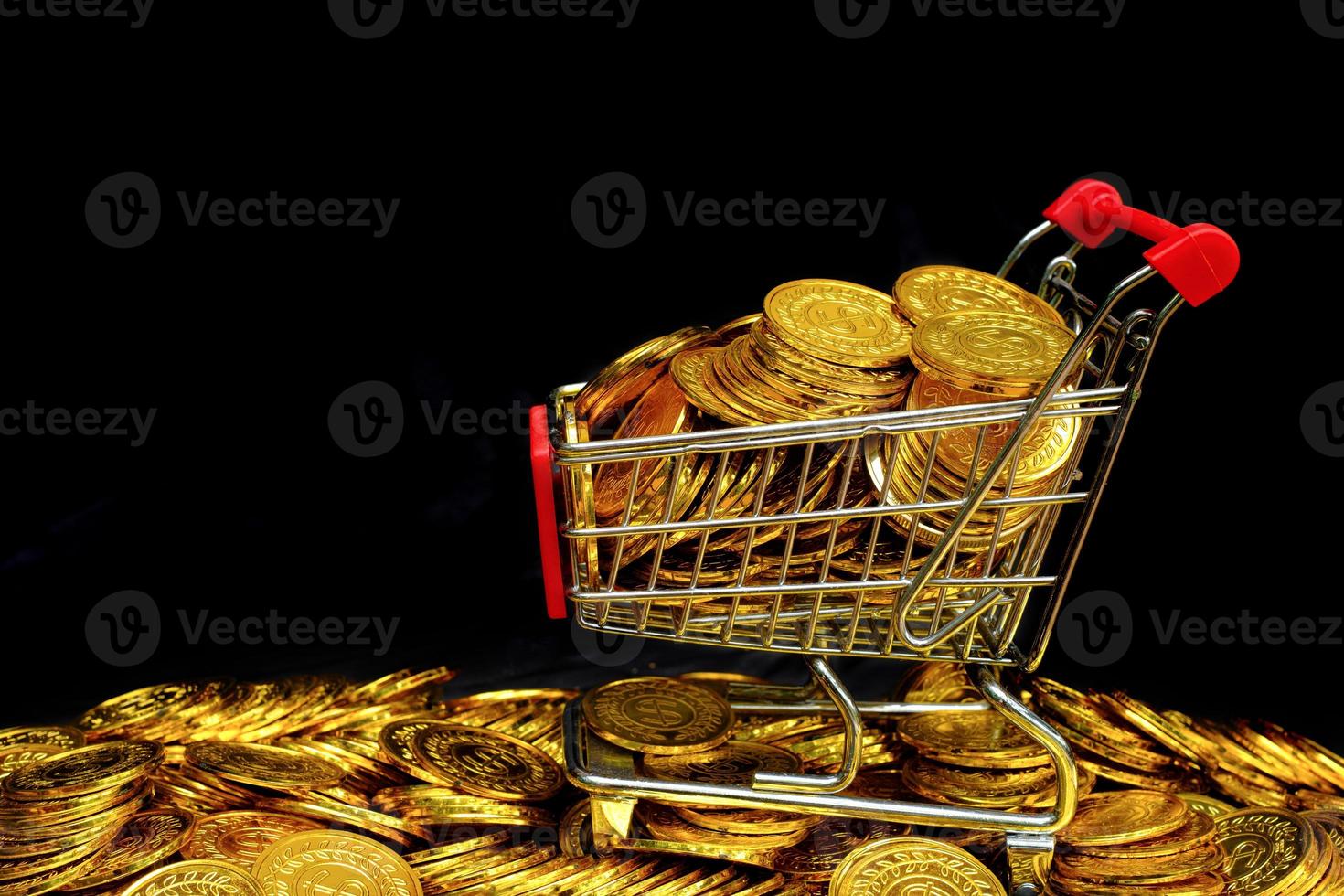 moneda de oro en el carro de la compra en un apilamiento de monedas de oro en fondo negro foto
