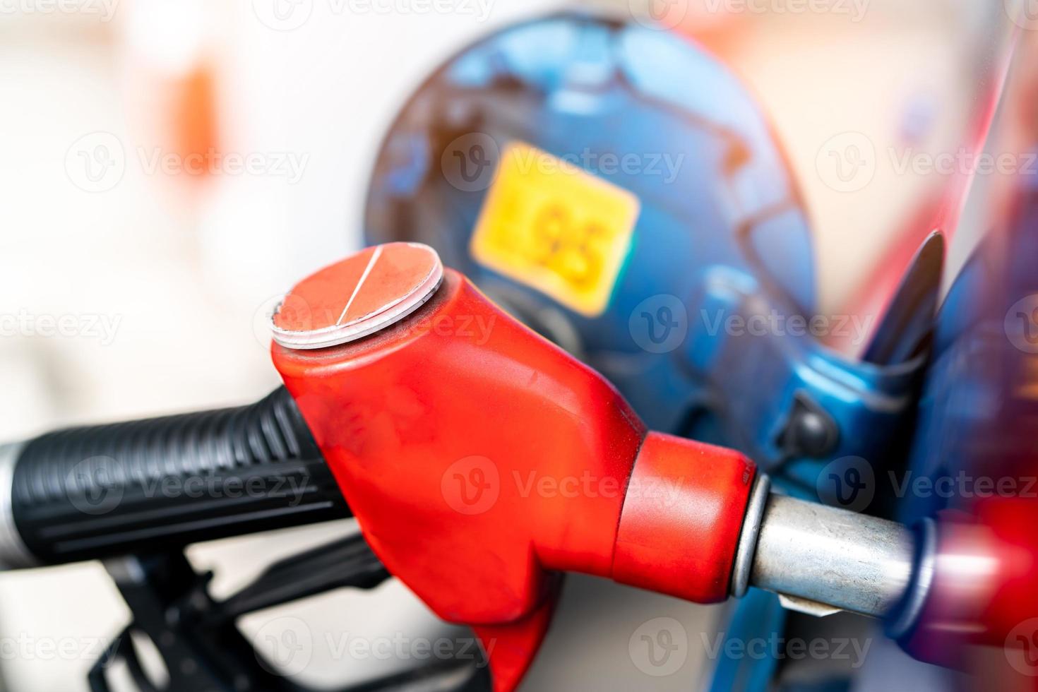 Close-up red fuel nozzle. Gasoline pump nozzle. Car fueling at gas station. Refuel fill up with petrol gasoline. Petrol pump filling fuel nozzle in fuel tank of car at gas station. Oil price crisis. photo