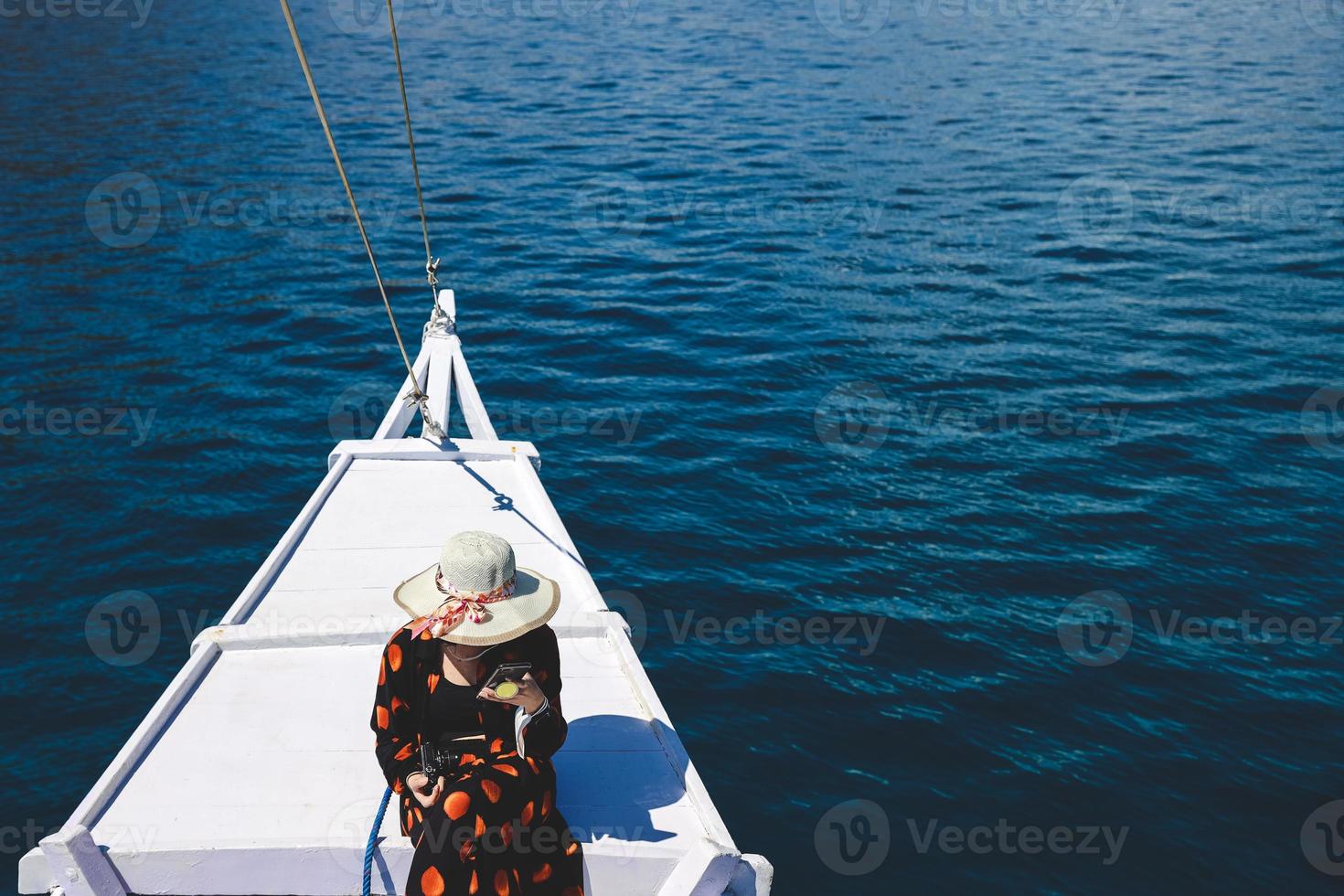 Women tourist in summer hat sitting on boat deck enjoying trip at Labuan Bajo photo